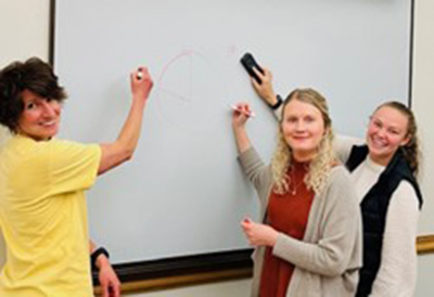 students standing and writing on whiteboard