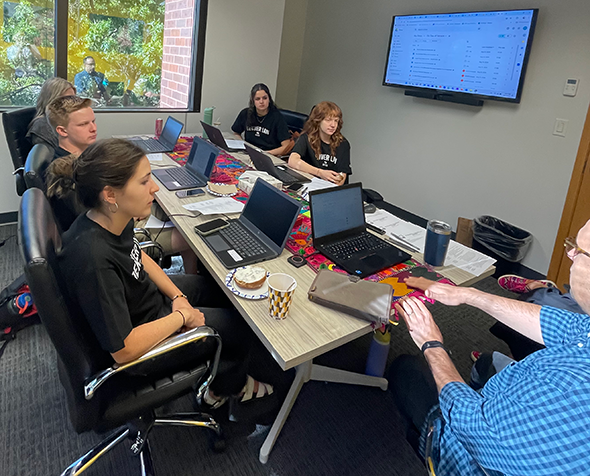 Photo of students seated at table in office