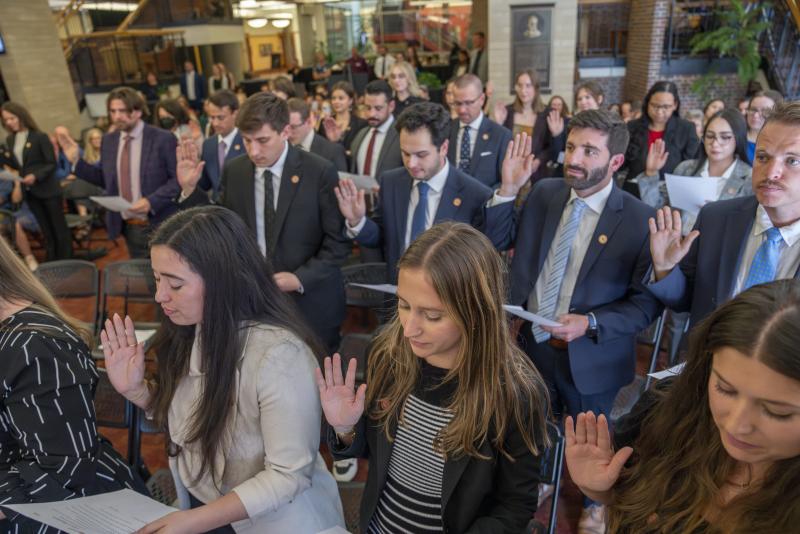 A group of law students hold up their right hands as they are sworn in as new student attorneys.